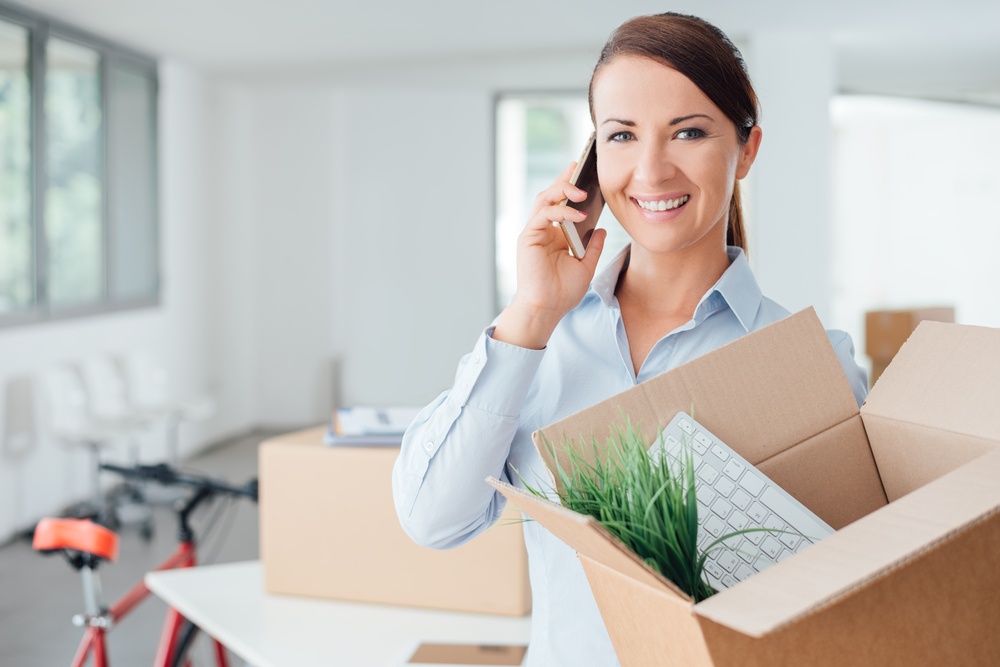 (Image) shutterstock_291771824 woman on mobile phone holding cardboard box