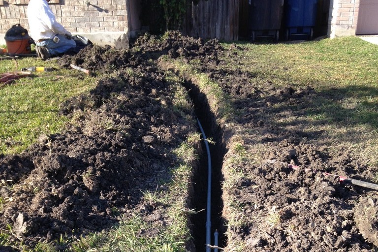 Plumbers lay new water line in a freshly dug trench. 