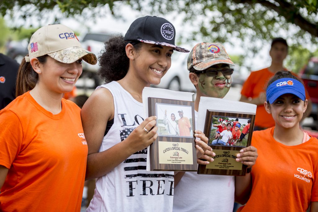 (Image) Volunteers celebrate a fun day of fishing with participants at last year's Kids Fish Day. Each participant was awarded a special plaque with a picture of their catch.
