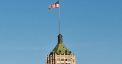 US flag flying high at a downtown building
